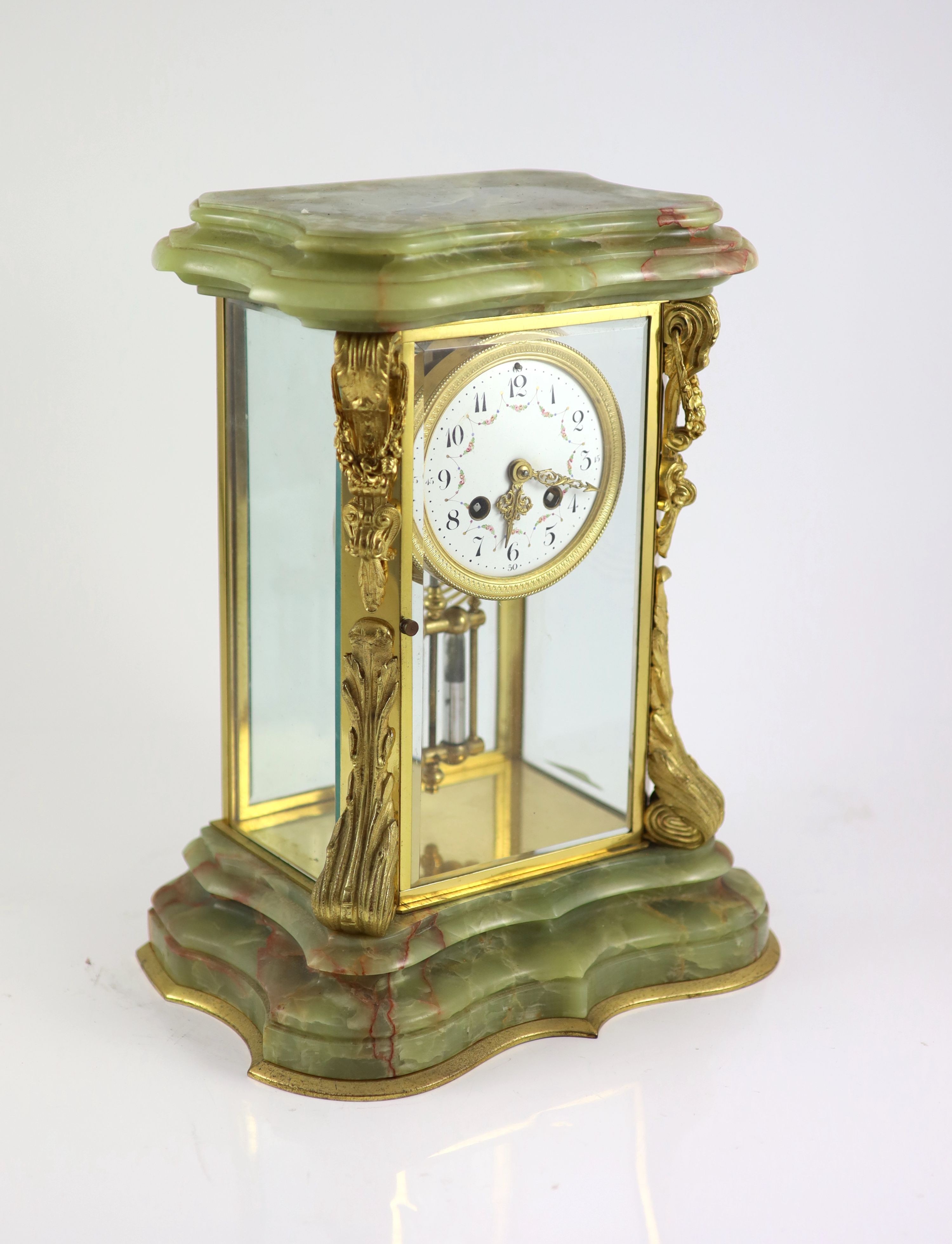 A green onyx and gilt metal clock garniture, comprising a four-glass regulator with enamelled dial in serpentine case and a pair of pedestal urns and covers Clock H 35cm. W 27cm. Urns H 36cm.